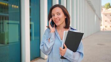 une femme est en portant une dossier et parlant sur le téléphone video