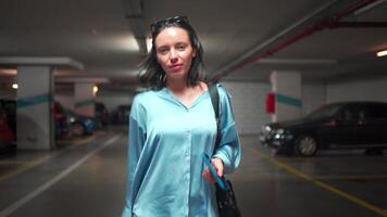 een vrouw in een blauw overhemd wandelen in een parkeren Oppervlakte video