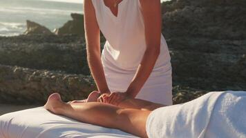 kvinna njuter professionell spa hand massage liggande på särskild tabell på strand under semester. massage terapeut ger avkopplande massage klientens vapen och axlar video