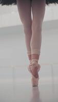 vicino su di bellissimo balletto del ballerino gambe nel punta. donna pratiche esercizi. di ballerina piedi nel scarpe. ragazza Spettacoli classico balletto passato. verticale formato per il Telefono. video