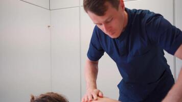 Professional therapeutic massage in the clinic. Masseur massages back and shoulders female patient who lies on massage table in massage room. video