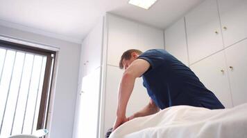 professioneel therapeutisch massage in de kliniek. masseur massages terug en schouders vrouw geduldig wie leugens Aan massage tafel in massage kamer. video