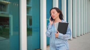 een vrouw in een blauw overhemd pratend Aan een cel telefoon video