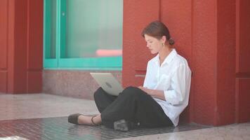 a woman sitting on the ground with a laptop video