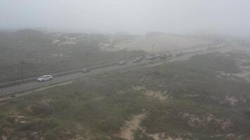 hoog verkeer Aan weg door zand duin mystiek mist. video