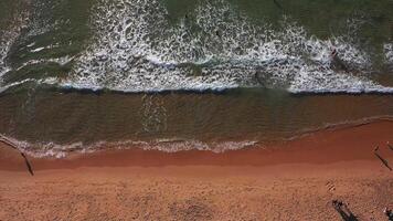 aéreo Visão do onda em a de praia com areia e turquesa ondas video