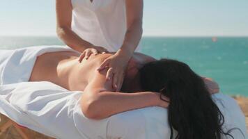 mulher desfrutando profissional spa mão massagem deitado em especial mesa em de praia durante período de férias. massagem terapeuta dando relaxante massagem do cliente braços e ombros video