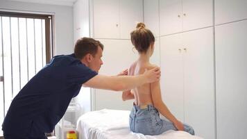 male massager giving therapeutic and relaxing, deep tissue stimulating back massage to a Caucasian female patient video