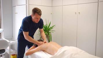masculino massageador dando terapêutico e relaxante, profundo lenço de papel estimulante costas massagem para uma caucasiano fêmea paciente video