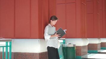 a woman is standing on a sidewalk holding a book video