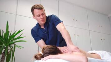 male massager giving therapeutic and relaxing, deep tissue stimulating back massage to a Caucasian female patient video