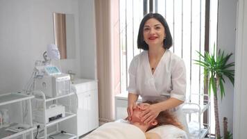 massage thérapeute masser diriger, épaules et cou à femme dans cosmétologie clinique. esthéticien fabrication soin de la peau et stimulation procédure. spa traitement et massage dans beauté salon Haut vue video