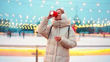 een vrouw in een winter jas staand dichtbij naar ijs baan video