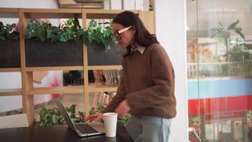 Serious smiling businesswoman working on laptop standing at office desk, female executive professional entrepreneur using computer corporate software doing paperwork at workplace drinking coffee video