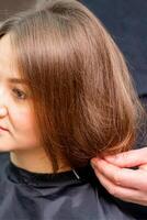 peinado hembra cabello. masculino peluquero hace peinado para un joven mujer en un belleza salón. foto
