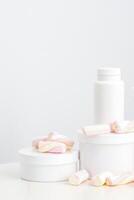 cosmético protección de la piel embalaje. belleza producto en blanco antecedentes. blanco frascos con Malvaviscos en el blanco mesa. foto