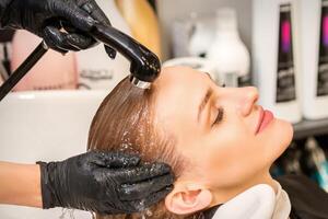 Young caucasian blonde woman having hair washed in the sink at a beauty salon. photo