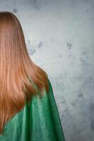 Rear View of a woman with long brown hair against a gray background. photo