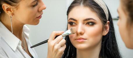 de cerca retrato de un mujer aplicando seco cosmético tonal Fundación en el cara utilizando un maquillaje cepillar. maquillaje detalle. foto