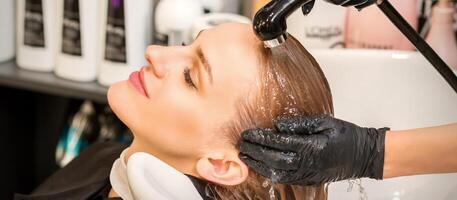 Young caucasian blonde woman having hair washed in the sink at a beauty salon. photo