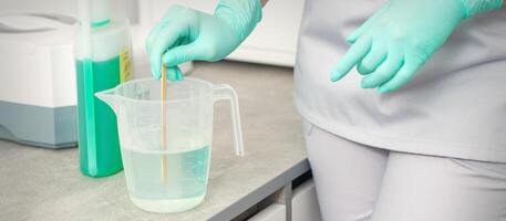 The beautician uses a stick to mix disinfectant into the water. Sterilization of tools. photo