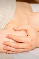 Male masseur massaging shoulder of a young woman lying on a massage table in a spa clinic. photo