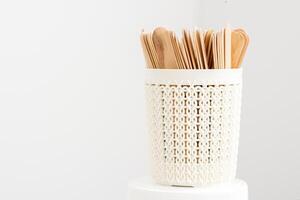 Sticks of wood for wax in white basket isolated on white background with copy space. photo