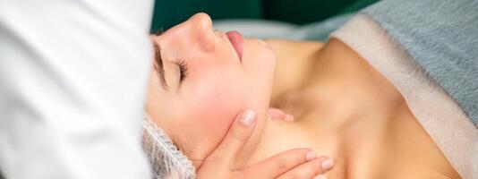 Massaging female neck. Young caucasian woman receiving neck massage relaxing in spa salon. photo