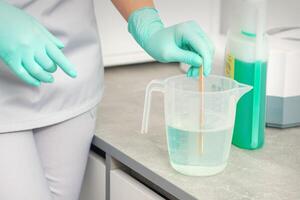 The beautician uses a stick to mix disinfectant into the water. Sterilization of tools. photo