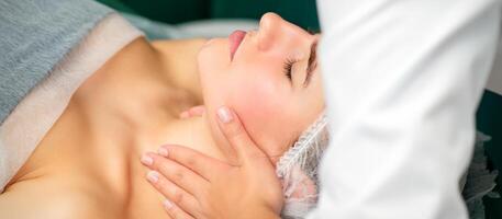Massaging female neck. Young caucasian woman receiving neck massage relaxing in spa salon. photo