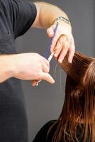 mujer teniendo un nuevo Corte de pelo. masculino estilista corte marrón pelo con tijeras en un pelo salón. foto