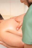 Physiotherapist giving shoulder massage to man in hospital. photo