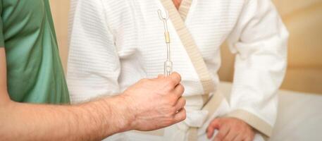 Doctor giving nasal inhalator with essential oil Maholda to a male patient in spa. photo