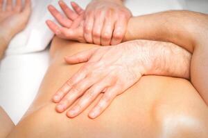 A male physiotherapist stretches the arms on the back of a man lying down, close up. photo