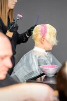 Coloring female hair in the hair salon. Young woman having her hair dyed by beautician at the beauty parlor. photo