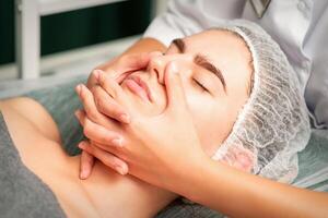 A young caucasian woman getting facial massage in a spa. photo