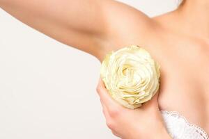 Close up of female armpit with white rose flower isolated on white background. photo