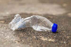 plastic bottle is laying on the ground, broken and discarded photo