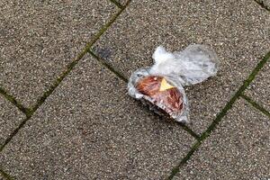 an old bread roll in a plastic bag on the street photo