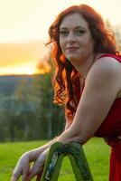 woman in a red dress and a ladder in a sunset photo