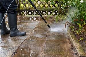 person is using a pressure washer to clean a brick patio photo