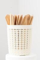 Sticks of wood for wax in white basket isolated on white background with copy space. photo