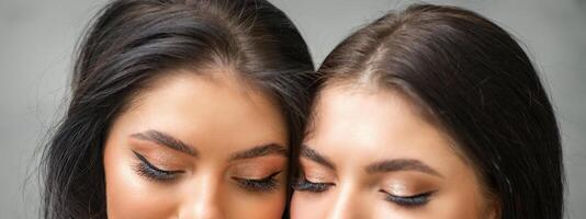 Portrait of young beautiful two women with long lashes and closed eyes after eyelash extensions. photo