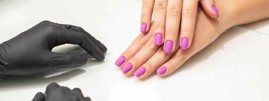 Beautiful fingers with purple nails after nail polish procedure in manicure salon. photo