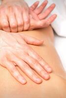 A male physiotherapist stretches the arms on the back of a man lying down, close up. photo