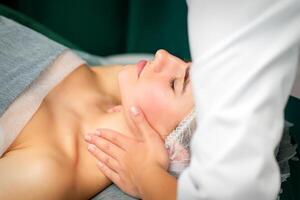 Massaging female neck. Young caucasian woman receiving neck massage relaxing in spa salon. photo