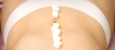 Sugar cubes lying in a row on abdomen of young woman, the concept of intimate depilation, problems of intimate hygiene. photo