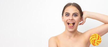 Happy expression young nude woman with candy in mouth holds lollipop near armpit on white background, epilation, depilation, hair removal concept. photo