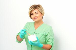 Cosmetician holding a jar of wax for depilation smiling on a white background. Natural product for hair removal. Copy space. photo