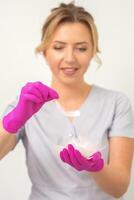 The beautician holds white feathers in her gloved hands over white background. Concept of health softness skin and body care. photo